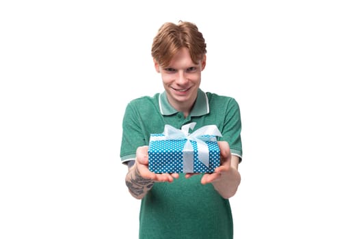 young european man with red hair holding out a gift box.