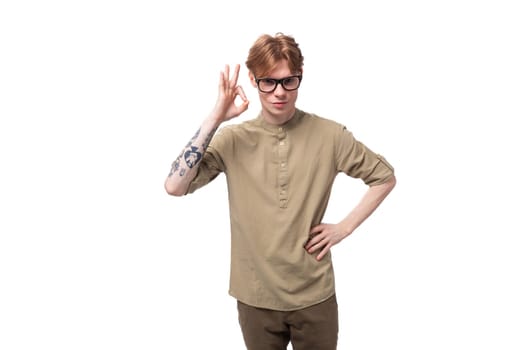 portrait of a handsome young caucasian man with red hair and a tattoo on his arm dressed in a khaki shirt.