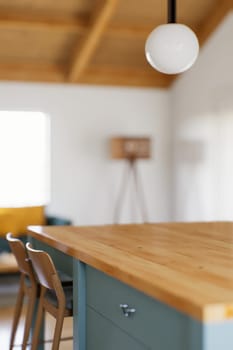 Kitchen with green cabinets, large window in the background and accent countertop to advertise the product. Kitchen island with blurry long shot of green kitchen. 3D rendering.