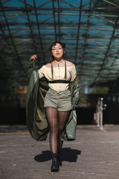 A beautiful Asian woman in shorts and a green leather coat comes out of the subway