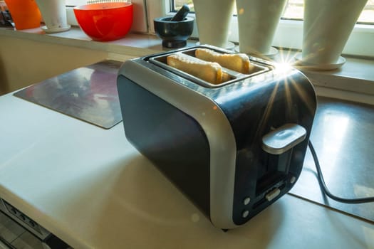 A toaster with slices of toast standing on the kitchen counter in sunny day