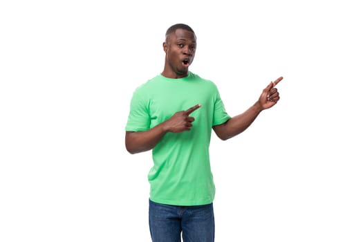 A 30-year-old African man dressed in a light green t-shirt points his hand at an advertisement.