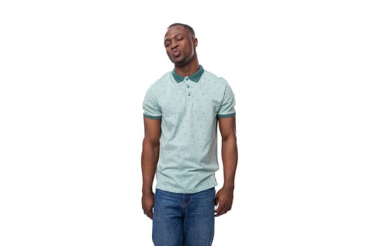 young shy african man dressed in a t-shirt and jeans stands thoughtfully.