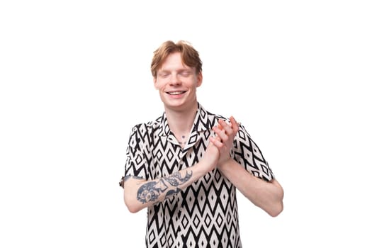 young stylish red-haired man dressed in a summer short-sleeved shirt in black and white.