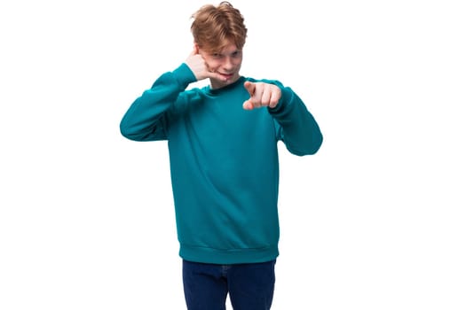 portrait of a handsome slender young european man with red hair in a blue sweater.
