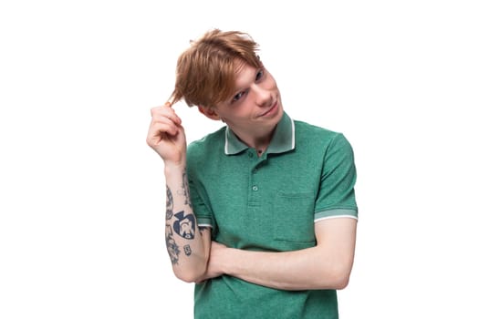 young red-haired caucasian guy in a green t-shirt daydreaming.