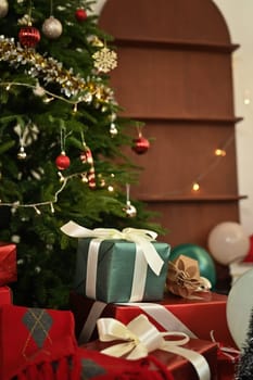 Pile of gift boxes near beautiful decorated Christmas tree. Winter holidays and celebration concept.