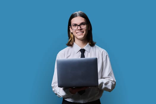 Handsome young male using laptop on light studio background. Positive smiling guy in white business shirt and tie looking at camera. Business, education, technology, communication, people concept