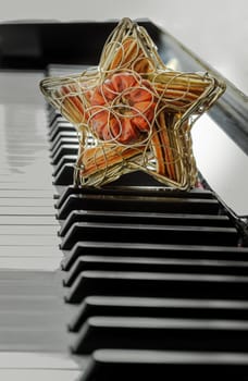 Golden star shaped mesh case is filled with dried fruits stand on the Piano Keyboard. Dried fruits in star shaped metal case on keyboard, Christmas decoration, Success concept, Space for text, Selective focus.