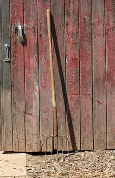 A Pitchfork leaning on a old red barn