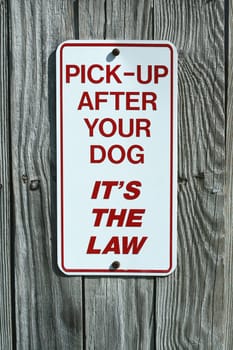 A Pick up after your dog sign on a fence