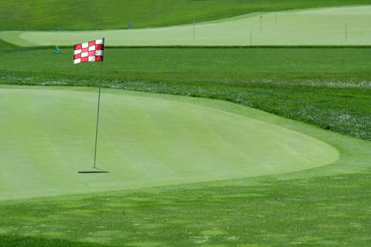 A Glof flag on a green with fairway