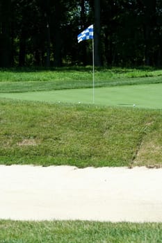 A Golf green with bunker in foreground