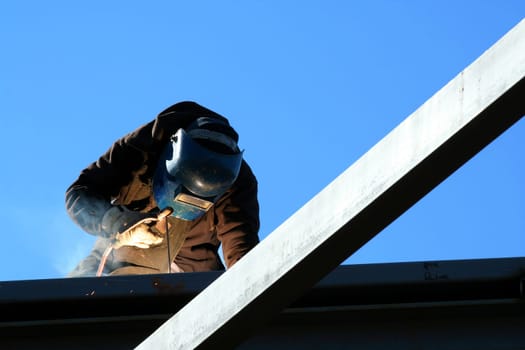 A welder on the roof of a construction site