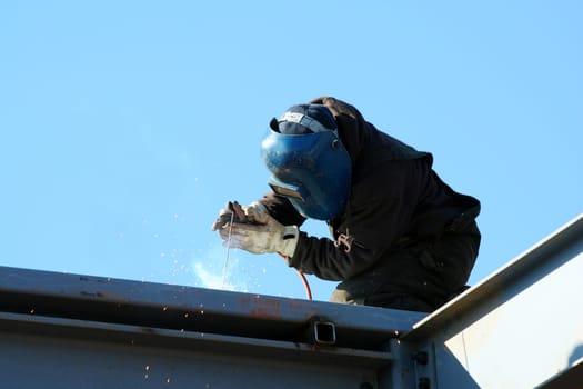 A welder on the roof of a construction site