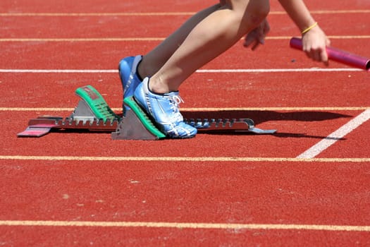 Runner leaving starting blocks with baton