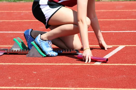 Runner in the starting blocks with baton