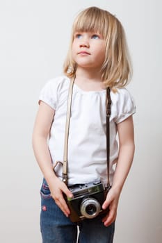 Little girl with an old camera. Studio shot.