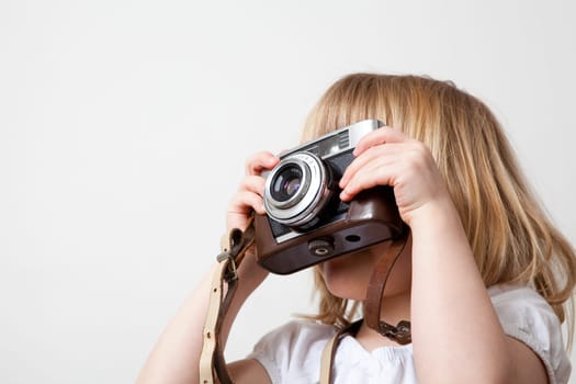 Little girl with an old camera. Studio shot.