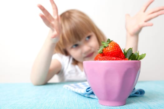 Little girl with a bowl of delicious strawberries