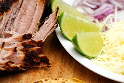 Pork Carnitas pulled apart ready to make tacos with fresh sliced lime