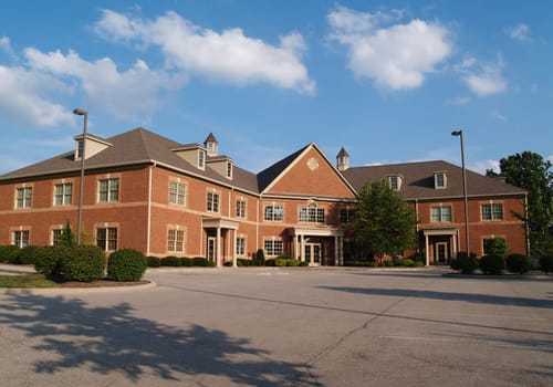 Two story red brick office building with parking spaces.