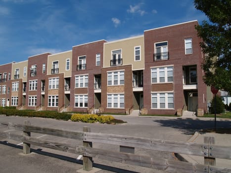 New townhouse or condo type homes made of different shades of brick and vinyl siding.