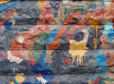 Colorful graffiti texture on the side of a public building in a variety of colors.