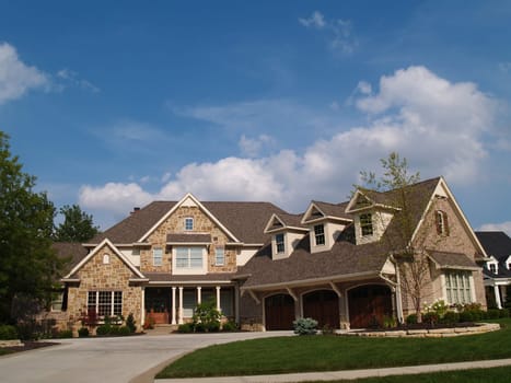 Large two story stone and brick residential home with garage in front containing plenty of copy space