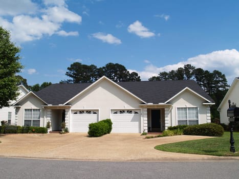 New low income small one story white vinyl duplex unit with garages in the front.