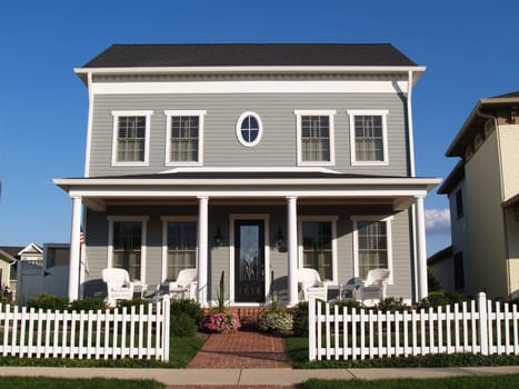 New two story vinyl home built to look like an old historical house with gray vinyl siding and large front porch.