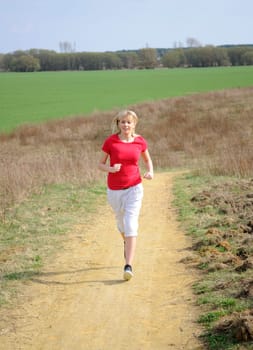 Young woman jogging on a dirt road