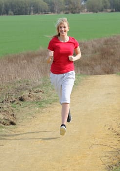 Young woman jogging on a dirt road