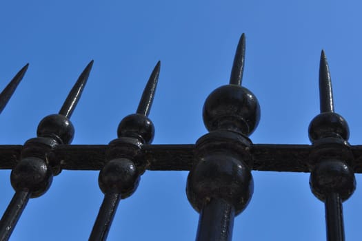 An iron metal fence over blue sky