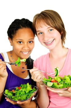 Isolated portrait of two teenage girls eating salad