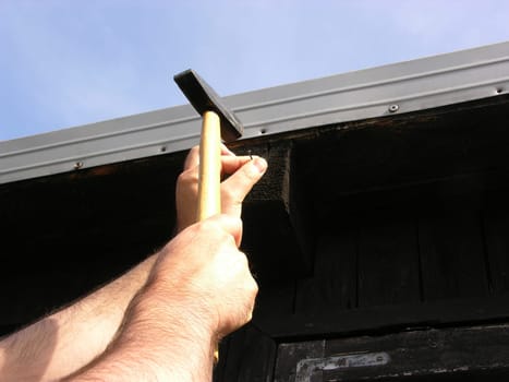 Man hammering a nail into wood with a hammer