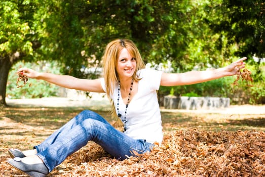 beautiful young model throwing leaves in park