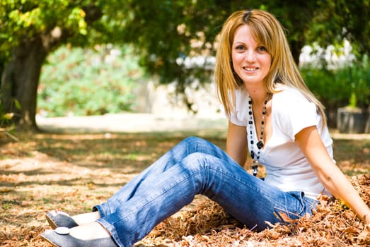 beautiful young model throwing leaves in park