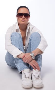 Young girl in tomboy style sit on ground - shirt and jeans