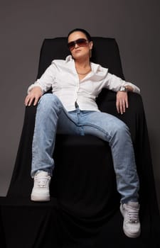 Young woman in tomboy style  sit on black chair