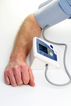 Male arm seen checking own blood pressure with an automatic monitor at home.