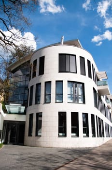 Modern white and gray architecture featuring square column glass panels and great cloudy blue sky