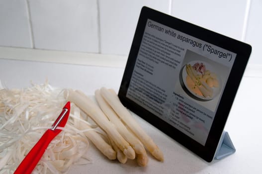 Modern Cooking with Digital Tablet PC displaying recipe of white asparagus
