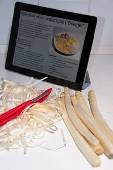 Modern Cooking with Digital Tablet PC displaying recipe of white asparagus