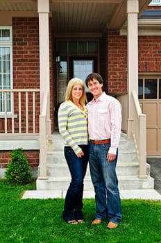 Young happy couple standing in front of house