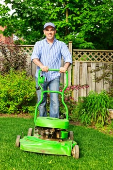 Man with lawn mower in landscaped backyard