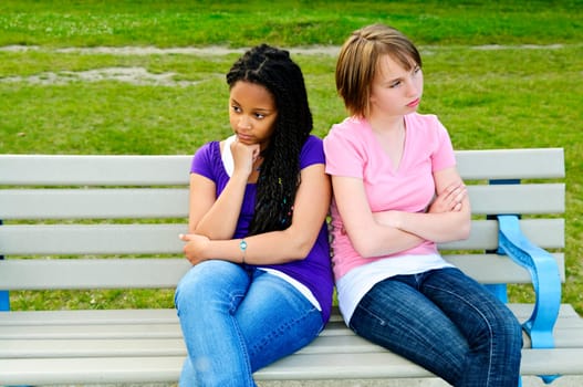 Two bored teenage girls sitting on bench