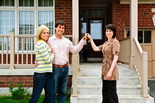 Happy couple getting keys to new house from real estate agent