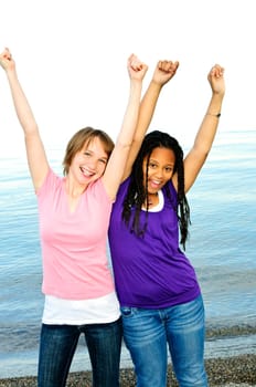 Portrait of two teenage girl friends raising arms