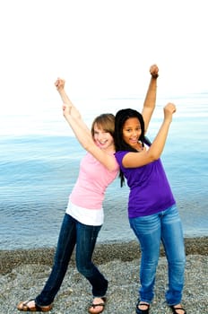 Portrait of two teenage girl friends raising arms